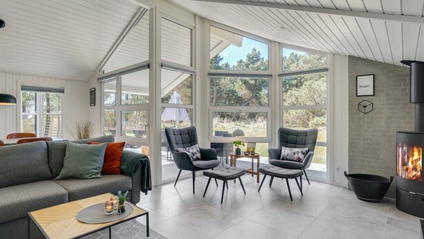 A spacious living room with a large fireplace, comfortable seating, and large windows offering a view of the outdoors. - "Edeltraut" - 900m from the sea by Interhome (Blåvand)