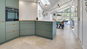 A modern kitchen with a herringbone tile backsplash, a built-in oven, and a large island with a light-colored countertop. - "Edeltraut" - 900m from the sea by Interhome (Blåvand)