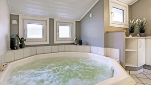 A bathroom with a large bathtub, two windows, a vanity with a mirror, and a potted plant on the counter. - "Stense" - 900m from the sea by Interhome (Blåvand)