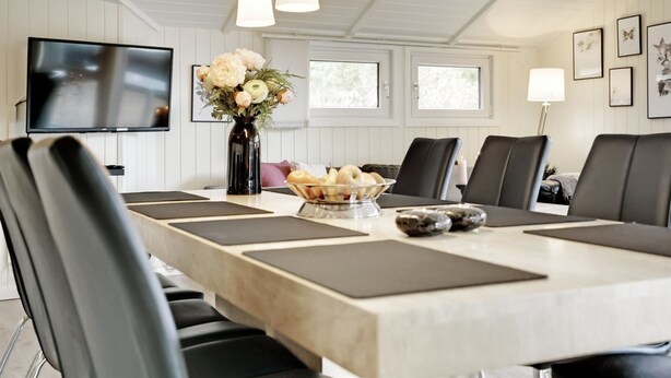 A dining area with a long table, black chairs, a vase of flowers, and a bowl of bread. - "Stense" - 900m from the sea by Interhome (Blåvand)