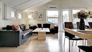 A spacious living room with a wooden floor, a sofa set, a dining table with chairs, and a large window with a view of the outside. - "Stense" - 900m from the sea by Interhome (Blåvand)