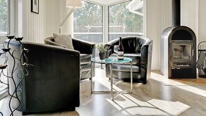 A modern living room with a fireplace, leather sofas, a glass coffee table, and a view through large windows. - "Stense" - 900m from the sea by Interhome (Blåvand)