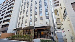 Un hôtel moderne avec une entrée en verre, de nombreux étages et une enseigne bien visible.