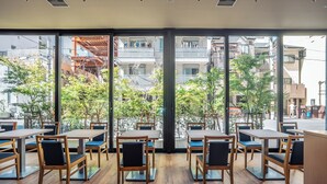 Un café moderne avec des tables et des chaises en bois, et de grandes fenêtres donnant sur la ville.