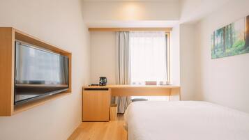 A compact hotel room with a bed, a desk, a television, and a painting on the wall.