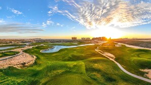 An aerial view of a golf course with a river, pathways, and distant buildings. - Las Palomas 3BR2BA OceanView Penthouse 1604 Cortez (Puerto Peñasco)