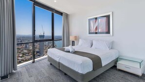A hotel room with a large window, a bed, a bedside table, and a framed picture on the wall. - Circle on Cavill Sky Home! (Gold Coast)