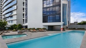 A modern building with a swimming pool, outdoor seating, and a lifebuoy. - Circle on Cavill Sky Home! (Gold Coast)
