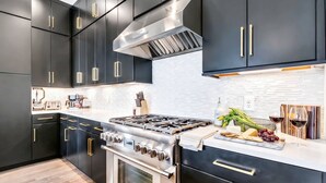 Uma cozinha moderna com armários escuros, eletrodomésticos de aço inoxidável e painel de azulejos branco.