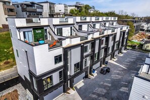 A modern multi-story residential building with balconies, large windows, and a flat roof.