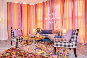 A room with a checkered sofa, two armchairs, a round coffee table, and a colorful rug.