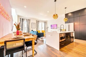 A modern kitchen with dark cabinets, a central island, and a dining area with a wooden table and chairs.