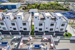 A modern building with multiple balconies, each equipped with outdoor seating and tables.