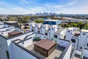A rooftop terrace with a view of a city skyline, featuring modern buildings and a river.