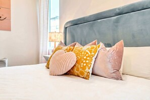 A neatly made bed with a variety of pillows and a headboard.