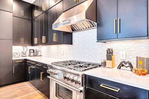 A modern kitchen with dark cabinetry, stainless steel appliances, and a white countertop.