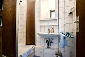 A bathroom with a white sink, a mirror, a towel rack, and a shower.