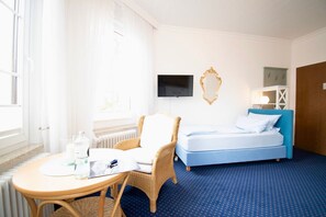 Una habitación de hotel con cama, televisión, silla, mesa y ventana.