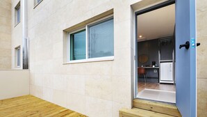 Un intérieur moderne avec un plancher en bois, un coin cuisine équipé d’un réfrigérateur et une porte donnant sur une autre pièce.