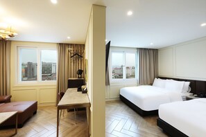 Habitación de hotel con cama, escritorio, silla y vista de la ciudad a través de grandes ventanales.