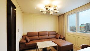 Un salon moderne avec un canapé en cuir marron, une petite table et une grande fenêtre donnant sur la ville.