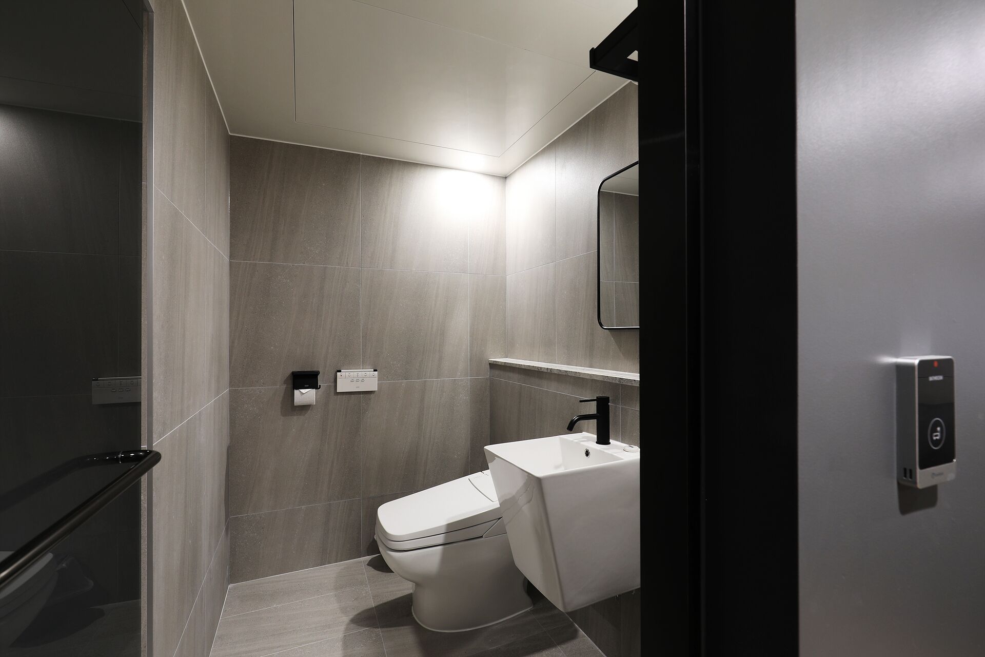 A modern bathroom with a toilet, a sink, and a shower area.