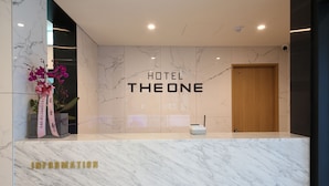 Un comptoir d’accueil à l’hôtel The One, doté d’un dessus en marbre et d’une porte en bois.