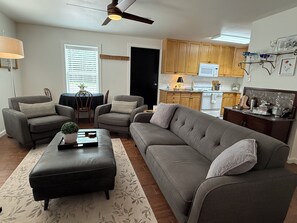 A living room with a sofa, two armchairs, a coffee table, and a dining area with a table and chairs.