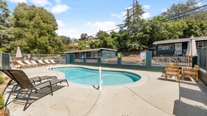 A swimming pool with lounge chairs and a small building, surrounded by a fence and trees. - The General Grant Cabin Near Sequoia w Pool (Three Rivers)