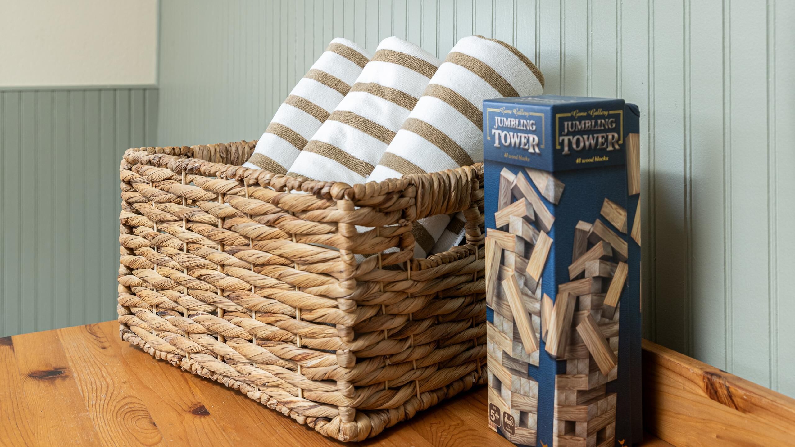 A woven basket with striped cushions and a box of wooden blocks labeled "Jumbling Tower".