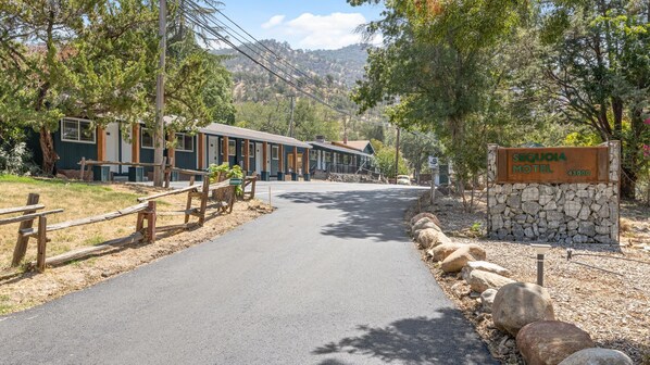 A road leading to a row of cabins with a stone sign for the Sequoia Hotel.
