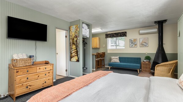 A bedroom with a bed, dresser, TV, and a fireplace.