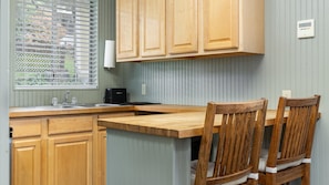 A kitchen with wooden cabinets, a countertop, a sink, and a window with blinds.