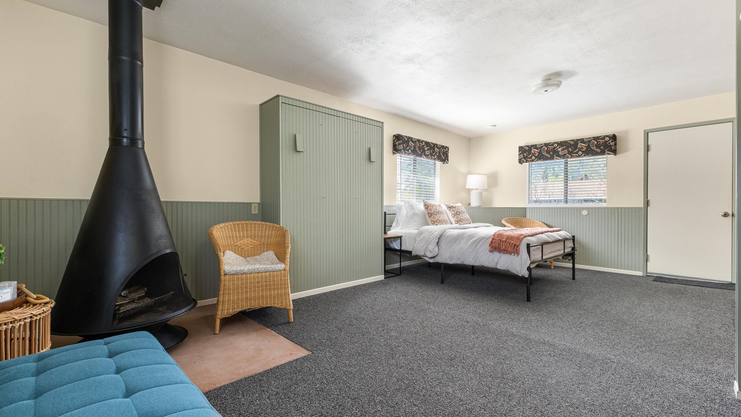A room with a bed, a chair, a fireplace, and a door.