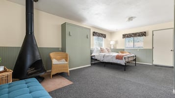 A room with a bed, a chair, a fireplace, and a door.