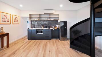 A modern kitchen with a central island, built-in shelves, and a black spiral staircase.