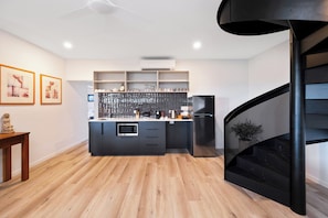 Cozinha moderna com ilha central, prateleiras embutidas e escada espiral preta.