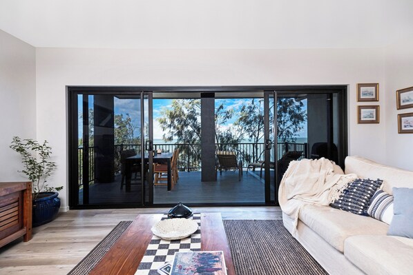 A modern living room with a large sliding glass door leading to an outdoor deck.