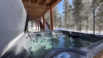 Relax in a hot tub surrounded by serene winter scenery.