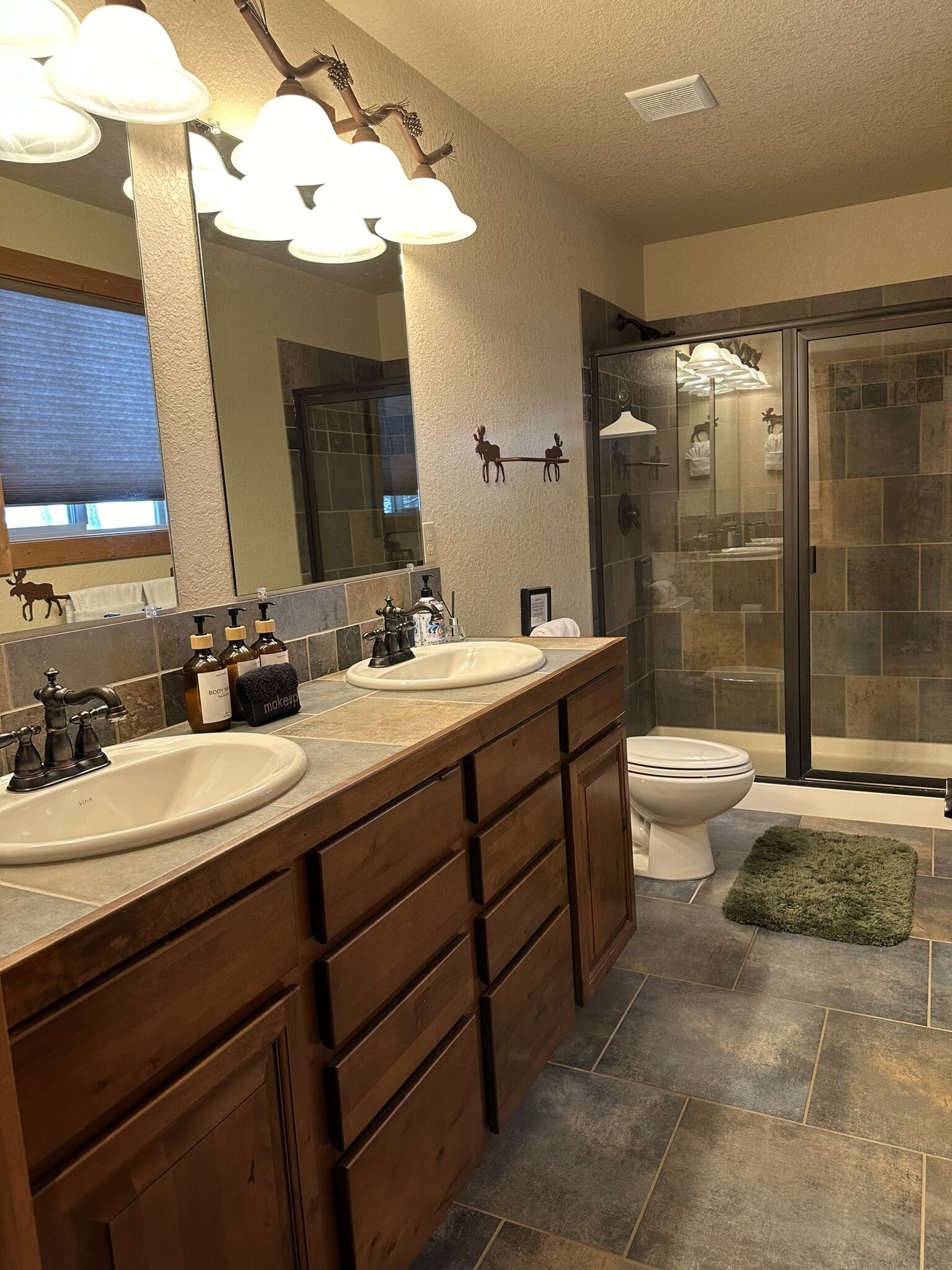 A bathroom with two sinks, a large mirror, and a glass shower enclosure.