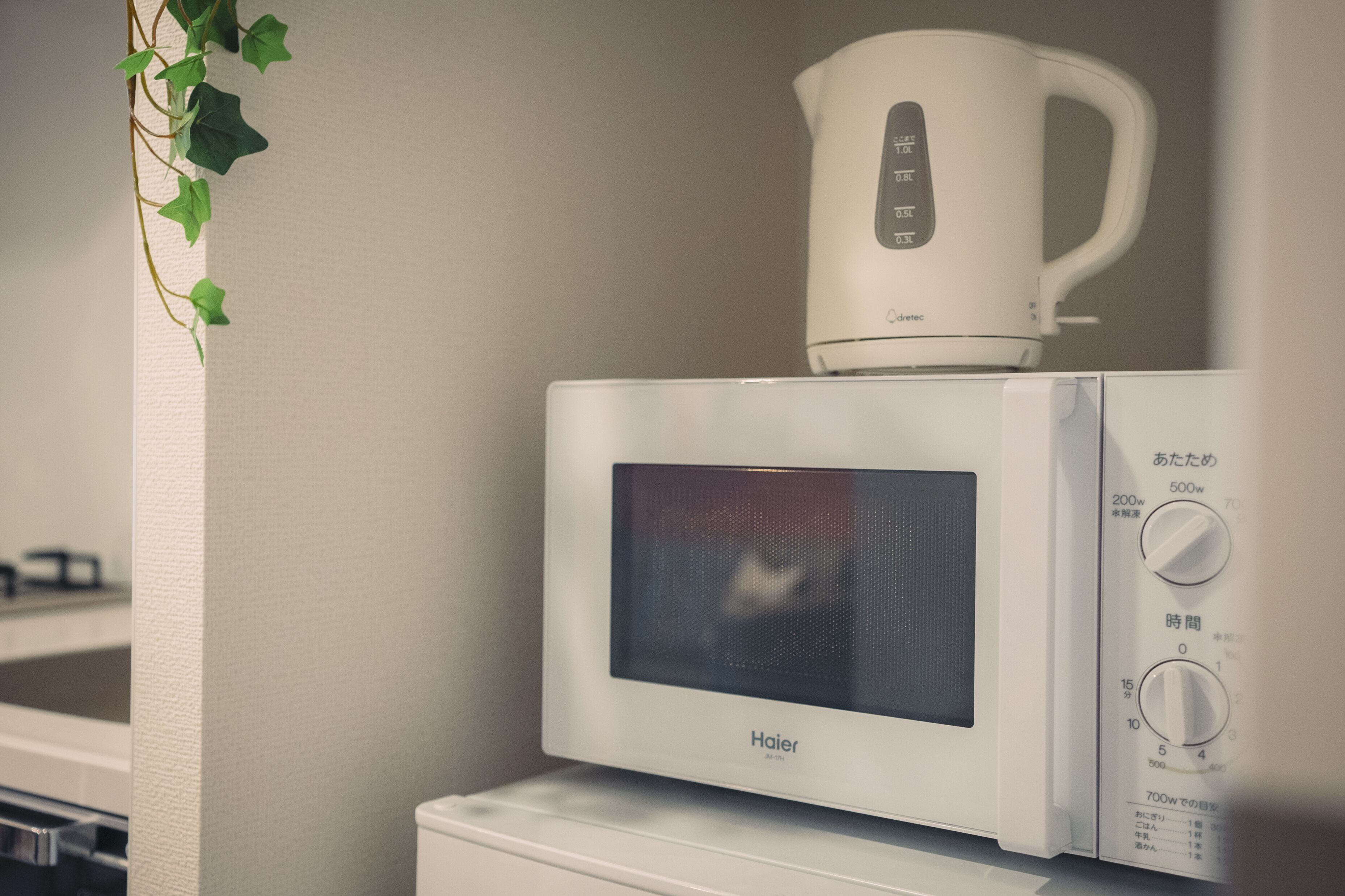 Un four à micro-ondes blanc doté d’un écran numérique et d’un panneau de commande, placé sur le dessus d’un appareil électroménager blanc, vraisemblablement un réfrigérateur.