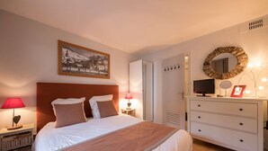 A neatly arranged bedroom with a bed, bedside lamps, a dresser, a TV, and a framed picture. - La Clusaz Primevères summer (La Clusaz)