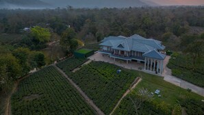 Una extensa propiedad con un edificio principal, amplios jardines y vistas del paisaje circundante.