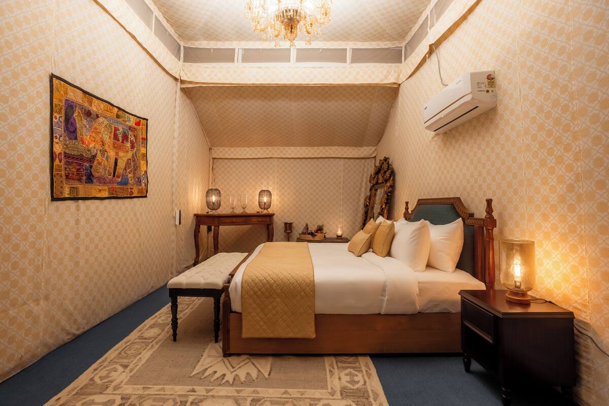 Une chambre à coucher comprenant un lit, des tables de chevet, un banc, un lustre et un appareil de climatisation.