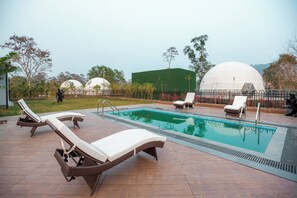 A swimming pool with lounge chairs and a fenced area.