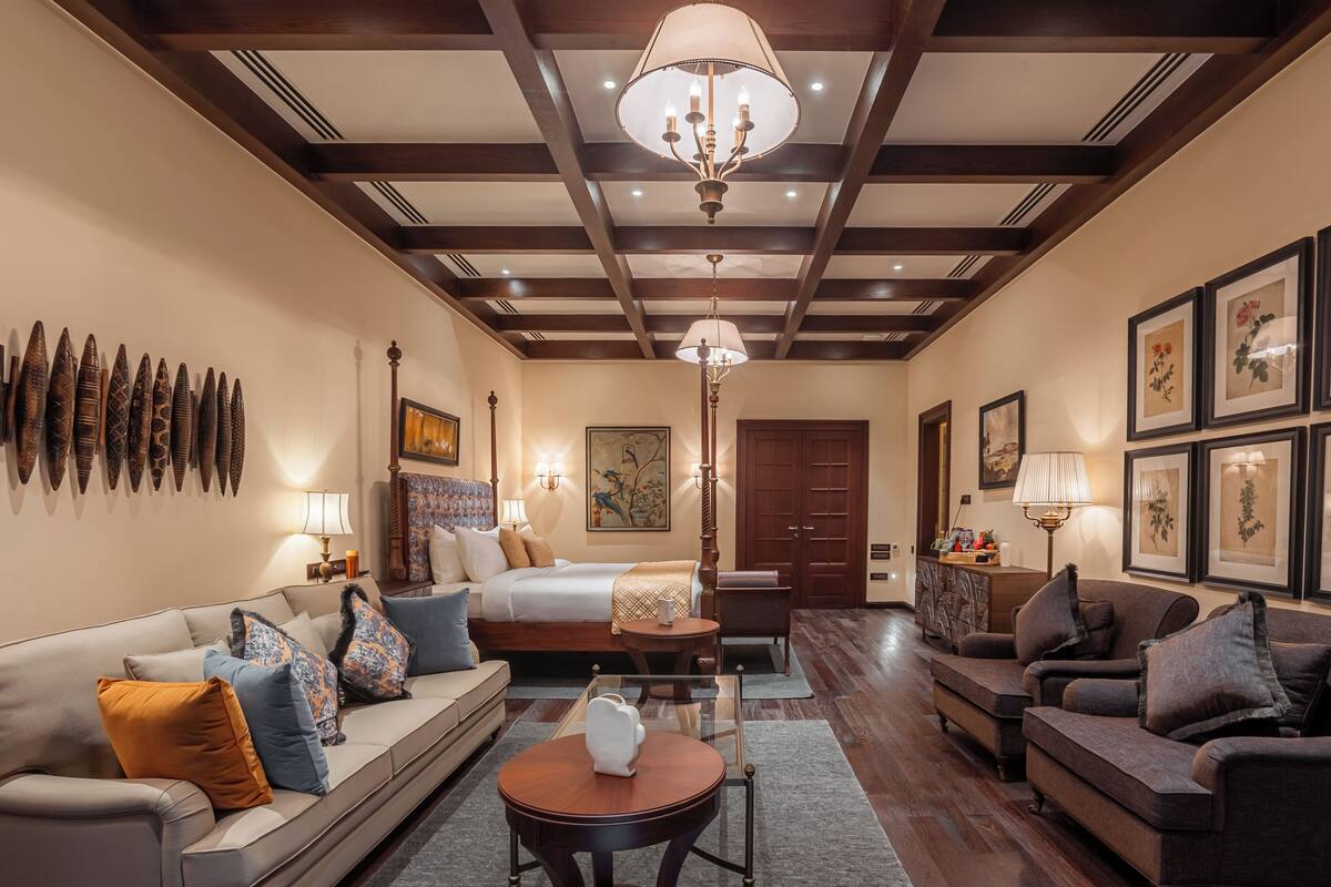 Une chambre d’hôtel avec un lit, deux canapés, une table basse et un lustre.