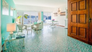 Una habitación con zona de comedor, vista al mar y una puerta grande de madera.