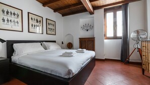 A neatly made bed with white linens and towels, a wooden headboard, and a ceiling fan. - Italianway - Bigli 6 (Milan)
