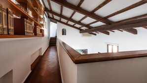 A narrow hallway with wooden bookshelves on the left and a staircase on the right. - Italianway - Bigli 6 (Milan)