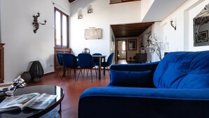 A living room with a blue sofa, a dining area with blue chairs, and a kitchen visible in the background. - Italianway - Bigli 6 (Milan)